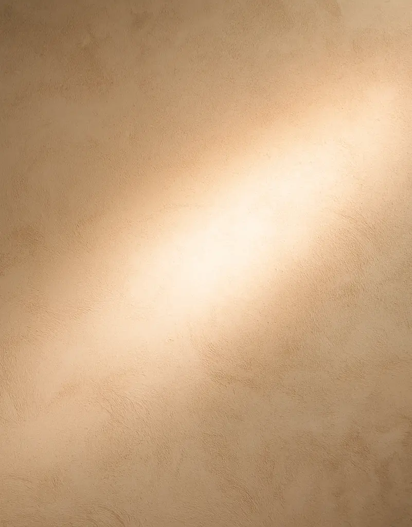 A soft beam of sunlight cast across a warm-toned plaster wall.