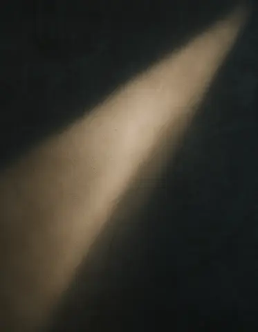 A focused beam of warm light illuminating a dark textured wall.