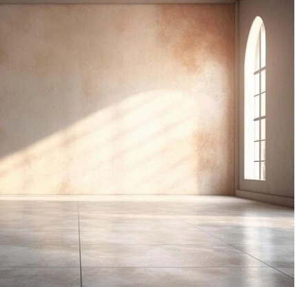 Sunlight streams through an arched window onto a textured beige wall in a minimalist interior.